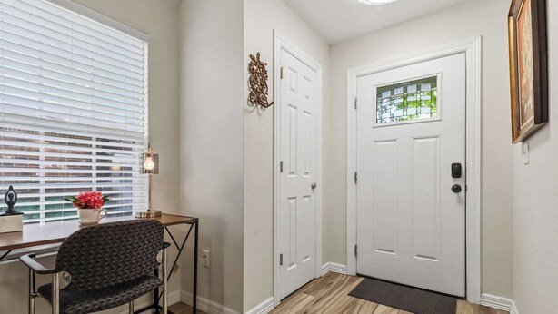 A hallway with a wooden floor, a white door with a window, a bench, and a wall-mounted light fixture. - Beaver Lake Getaway - Fenced Yard, Pets OK (Springdale)
