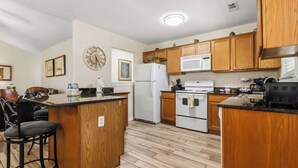 A kitchen with wooden cabinets, a refrigerator, a microwave, and a stove. - Beaver Lake Getaway - Fenced Yard, Pets OK (Springdale)
