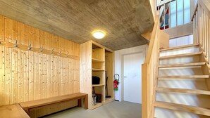 A wooden interior with a bench, a fire extinguisher, and a staircase.