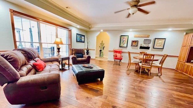 A spacious living room with a brown leather sofa, a coffee table, and a dining area with wooden chairs and a table. - Enjoy 3 King beds with ensuite baths, 8 total beds (Fayetteville)