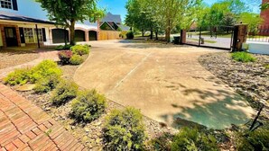 A residential driveway with a paved surface, surrounded by landscaped areas and trees. - Enjoy 3 King beds with ensuite baths, 8 total beds (Fayetteville)
