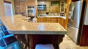 A kitchen with a large island, built-in oven, microwave, and stainless steel refrigerator.