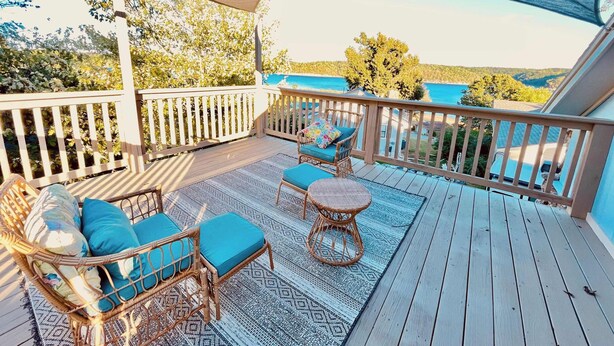 A wooden deck with wicker furniture and a view of the sea.