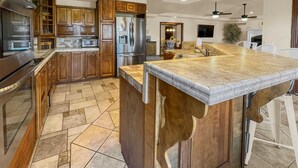 A modern kitchen with wooden cabinets, stainless steel appliances, and a large island with a butcher block countertop.
