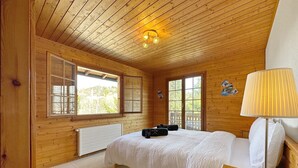 A wooden cabin bedroom with a bed, a nightstand, a lamp, and a window. - Chalet Albarose - Vercorin (Chalais)