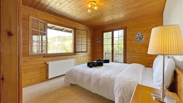 Une chambre à coucher dans une cabane en bois, avec un lit, une table de chevet, une lampe et une fenêtre.