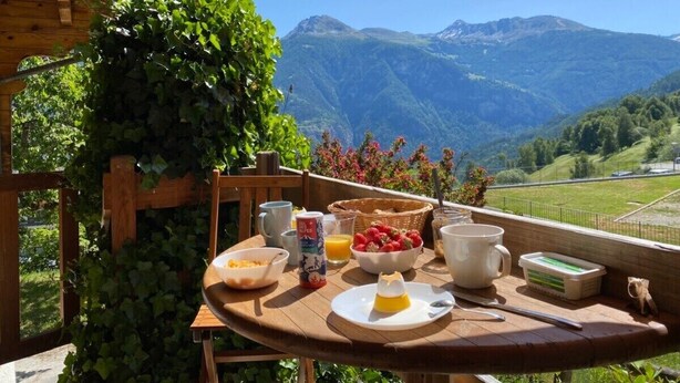A wooden table with breakfast items and a scenic mountain view. - Chalet Albarose - Vercorin (Chalais)
