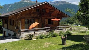 A rustic wooden chalet with a stone foundation, a wooden porch, and a red umbrella. - Chalet Albarose - Vercorin (Chalais)