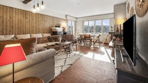 Ein großzügiger Wohnraum mit einer Holzwand, einem Sofa, einem Couchtisch und einem Fernseher.