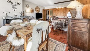 Ein gemütliches Wohnzimmer mit Kamin, Fernseher und Essbereich mit Holztisch und Stühlen.