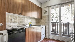 Eine Küche mit Holzausstattung, einem Geschirrspüler und einer gefliesten Rückwand.