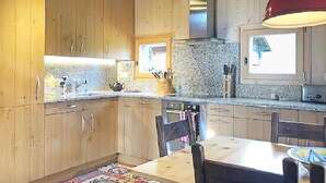 A kitchen with wooden cabinets, granite countertops, a red hanging light, and a window with a view of a building.