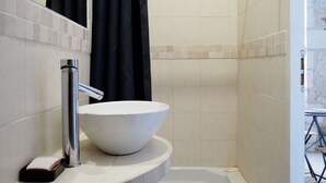 A modern bathroom with a white sink, a mirror, and a shower area. - Quiet nest with terrace in the city center (Avignon)