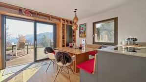 Eine moderne Küche mit einem großen Schiebeglasfenster, das auf eine Terrassenfläche hinausführt.