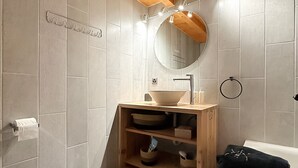 Une salle de bain moderne avec un plafond en bois, un miroir rond, un lavabo et des toilettes.