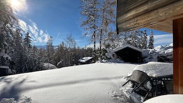 Un espace extérieur enneigé avec un chalet en bois, une chaise et une table.