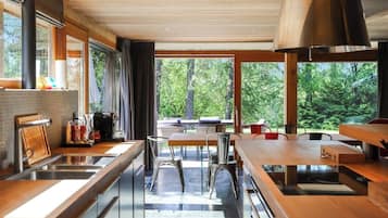 Une cuisine moderne dotée d’une grande fenêtre, de meubles en bois et d’un coin repas avec des chaises en métal.