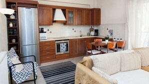 A modern kitchen with wooden cabinets, a stainless steel refrigerator, and a dining area with a table and chairs. - Cozy apt in Peristeri near Metro station (Peristeri)