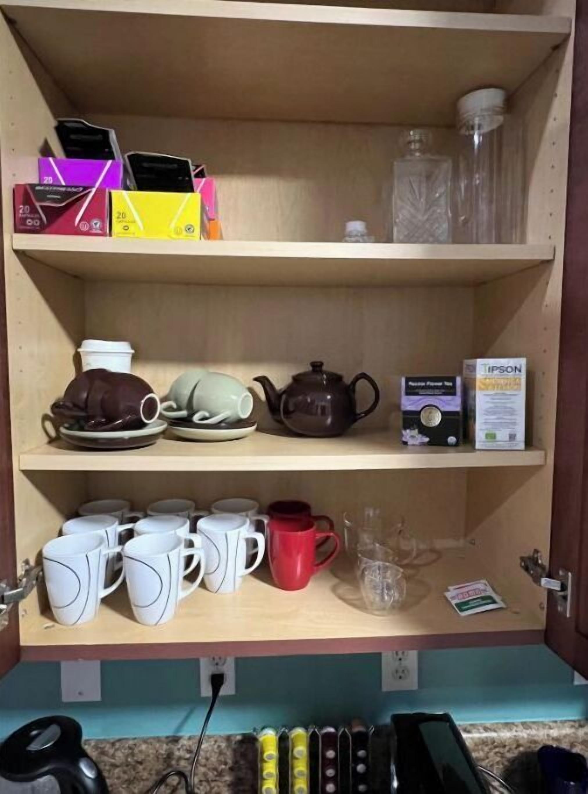 Une étagère de cuisine contenant divers objets, notamment une théière, des tasses et des boîtes.
