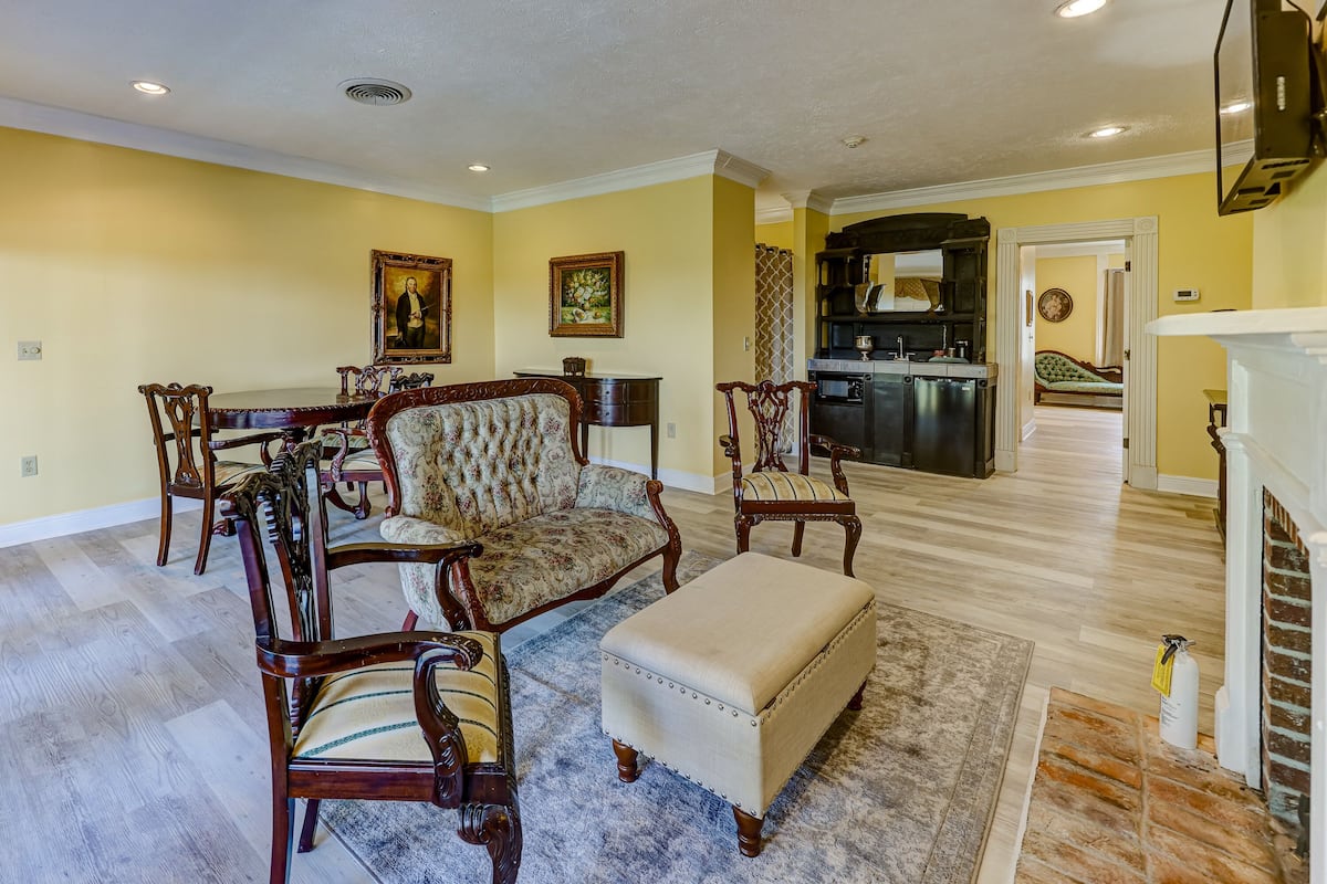 A living room with a dining table, two armchairs, a sofa, and a fireplace.