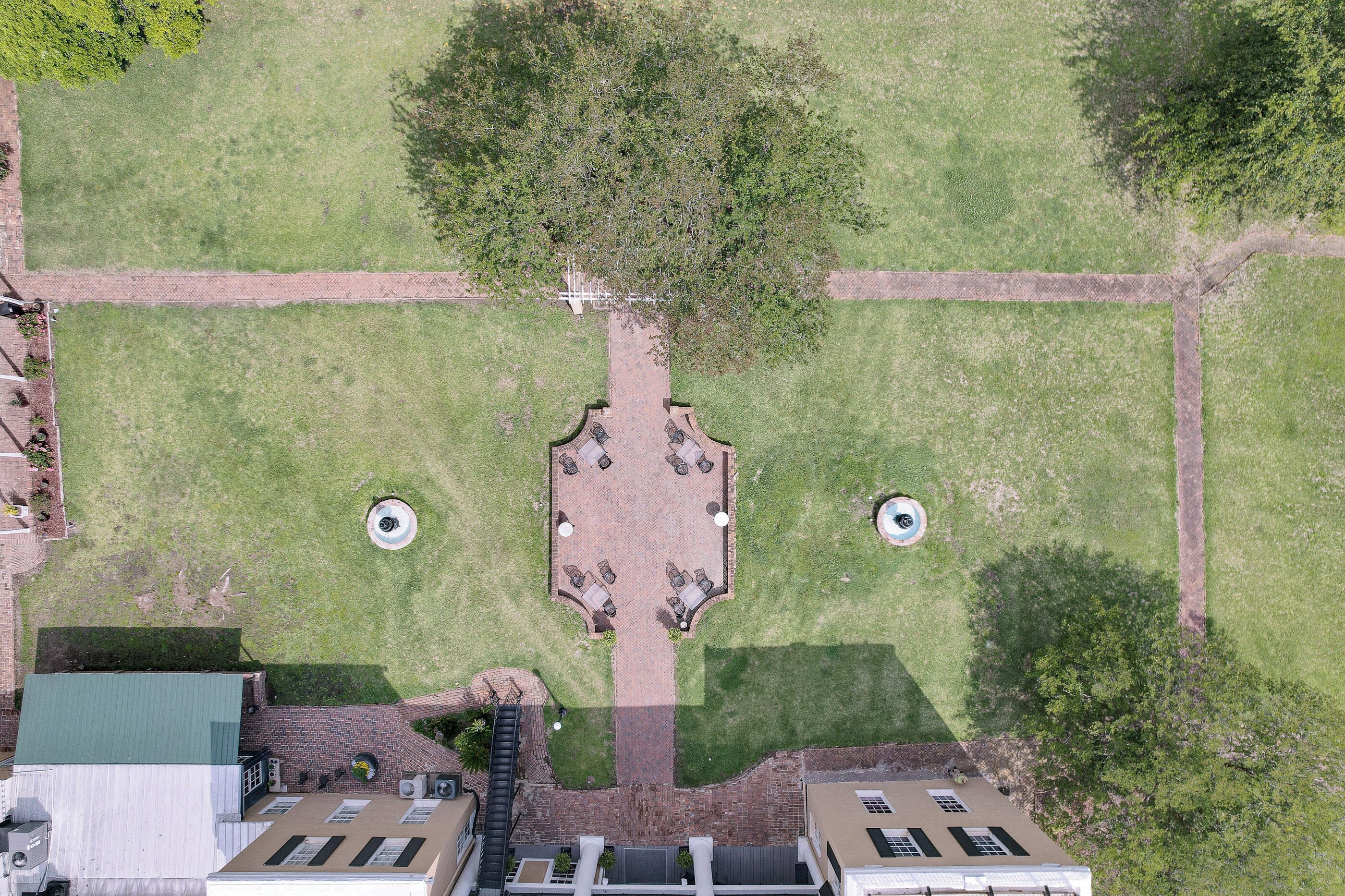 An aerial view of a courtyard with a central seating area, surrounded by trees and pathways.