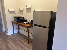 Una cocina compacta con refrigerador, microondas, cafetera y una mesa de madera.