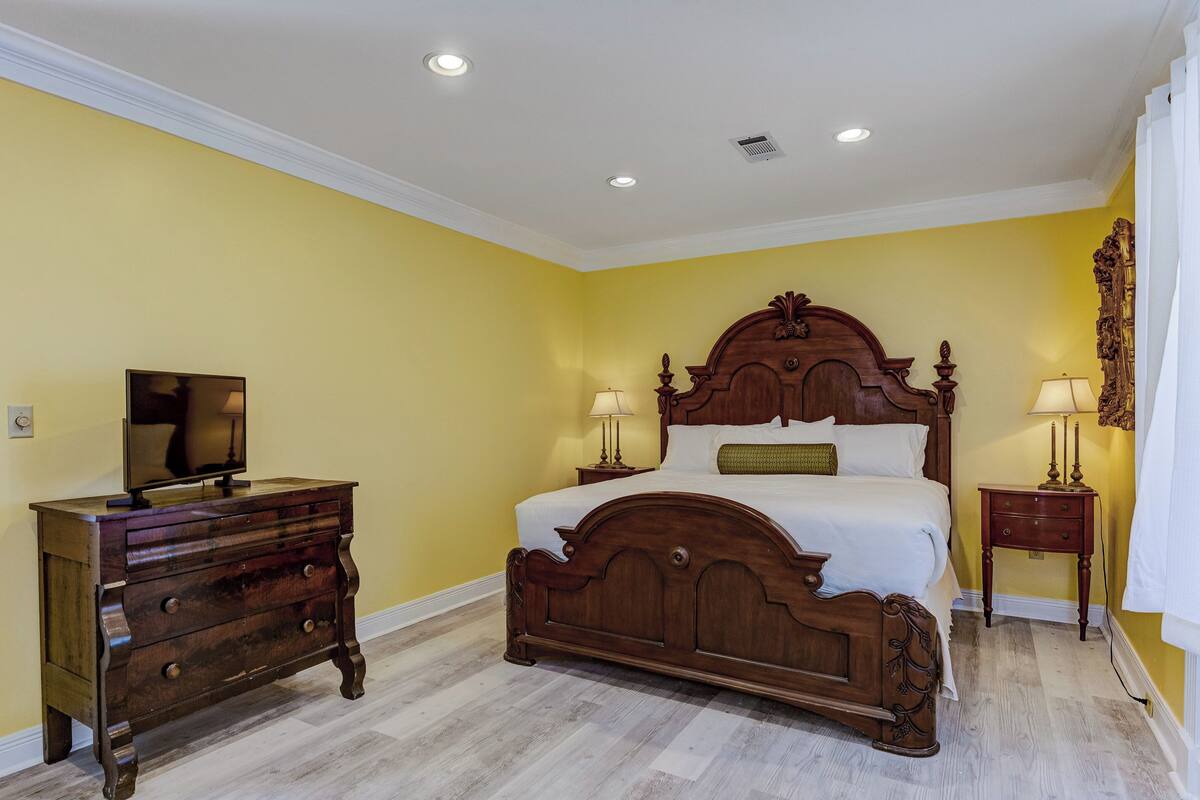 A bedroom with a wooden bed, a dresser, and a television.
