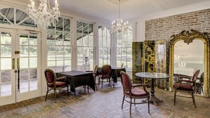 A room with a brick floor, large windows, and a chandelier. - The Inn at Cedar Grove (Vicksburg)