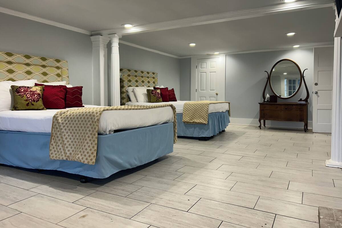 A bedroom with two beds, a dresser, and a mirror.