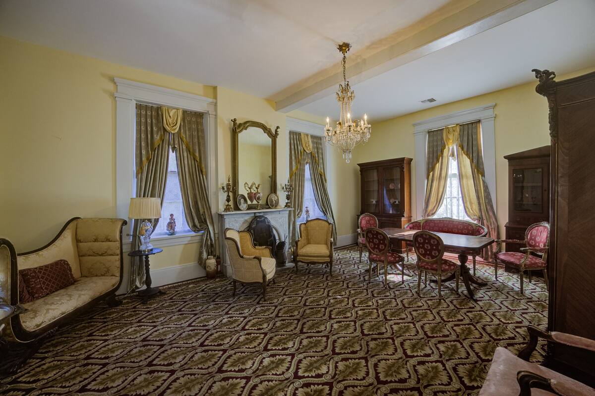 A room with a patterned carpet, a chandelier, and a dining set.