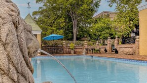 A stone fountain with water spouting into a pool, surrounded by brick walls and greenery. - The Inn at Cedar Grove (Vicksburg)