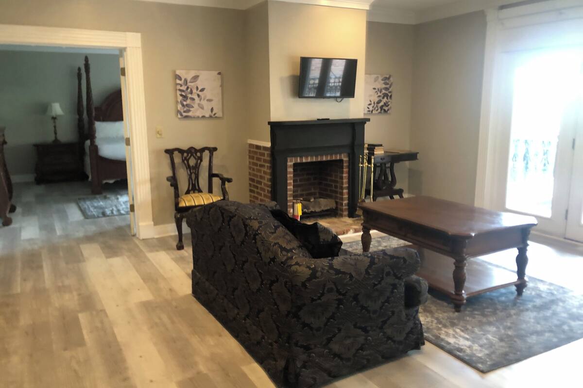 A living room with a fireplace, a television mounted above it, and a patterned sofa.