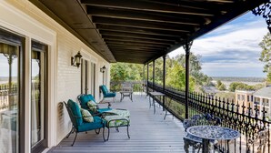 A covered porch with outdoor seating, a view of the landscape, and a railing. - The Inn at Cedar Grove (Vicksburg)
