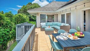 An outdoor patio area with a dining table set for breakfast, a sofa, and a railing overlooking a garden. - Mala Nani Hale Kiahuna Golf Course By Suite Paradise (Koloa)