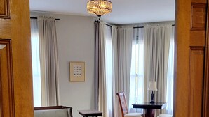 A room with a wooden floor, a patterned rug, a chandelier, a sofa, a chair, and a table. - The Elizabeth Inn and Restaurant (Bethel)