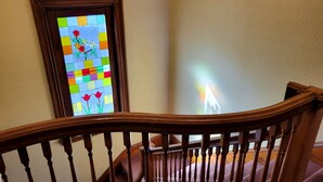 A wooden staircase railing with a stained glass window featuring flowers. - The Elizabeth Inn and Restaurant (Bethel)
