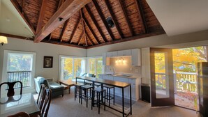 A spacious kitchen with a central island, wooden ceiling beams, and large windows offering views of autumn foliage. - The Elizabeth Inn and Restaurant (Bethel)