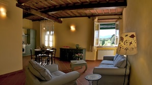 A cozy living room with striped sofas, a small table, and a view of a garden through a window. - "encantea" lovely country house - apartment "Timo" (Lucca)
