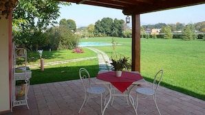 A patio with a table and chairs, a pool in the background, and a garden with a pathway. - "encantea" lovely country house - apartment "Timo" (Lucca)