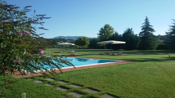 A swimming pool surrounded by a well-maintained lawn, with a mountain view in the background. - "encantea" lovely country house - apartment "Timo" (Lucca)
