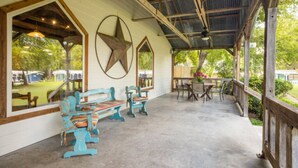 A covered patio area with rustic wooden beams, a large star decoration on the wall, and outdoor seating with colorful chairs. - Lodge 53 -Cozy Room right off the Lodge (Burnet)