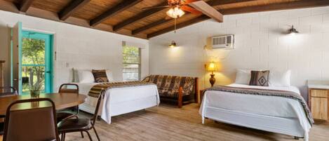 A room with two beds, a wooden dining table, and chairs.