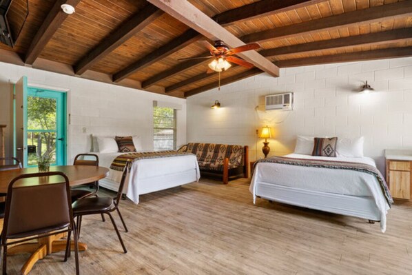 A room with two beds, a wooden dining table, and chairs.
