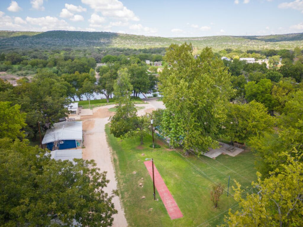 An aerial view of a property with a large open field, a red pathway, and a building with a blue roof.
