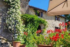 A stone building with a staircase, potted plants, and red flowers. - Monterotondo mountain villa with private pool, walk restaurant, WIFI. (Toscana)