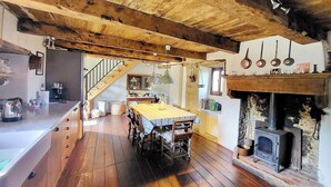 Una cocina rústica con pisos de madera, una mesa de comedor y un estufa de leña.