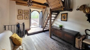 Una habitación rústica con una escalera de madera, una cama con almohadillas amarillas, un banco de madera y cuadros enmarcados en las paredes.