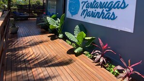 A wooden deck with a sign reading "Pousada Tartarugas Marinhas" and a covered seating area.