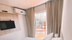 A hotel room with a bed, a TV mounted on the wall, and a window with curtains.