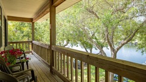 A wooden deck with chairs and a table, overlooking a lake and trees. - Condo 12, Lakefront with a Beautiful View (Burnet)